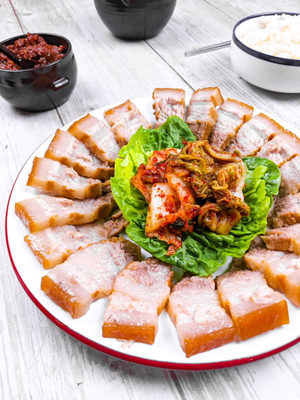 bossam, viande de porc bouillie servie avec du kimchi, de la salade et des banchans